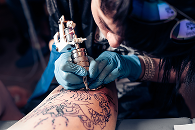 Un tatoueur se concentre sur la réalisation d’un tatouage